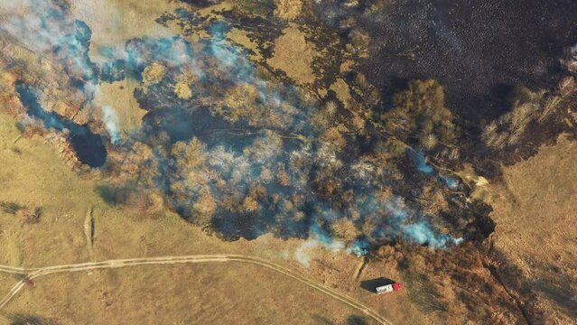 Aerial View. Spring Dry Grass Burns During Drought Hot Weather. Bush Fire And Smoke. Fire Engine, Fire Truck On Firefighting Operation. Wild Open Fire Destroys Grass. Ecological Problem Air Pollution.