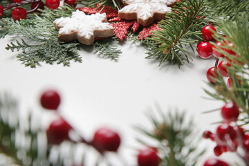 Fototapeta na wymiar Christmas decoration. Christmas tree branches, red berries and snow flake shaped cookies on white background.