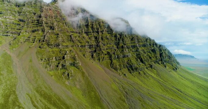 Shallow clouds hugging the ridge of a giantic mountain.