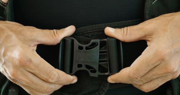 A close shot of a man locking the belt of a diving kit on his waist.