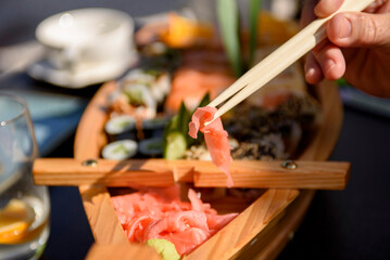 Set with spicy wasabi paste and pickled ginger on a wooden stand, top view. Maki and rolls with tuna, salmon, shrimp, crab and avocado.