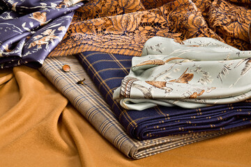 A composition of natural fine fabrics for women's clothing lying on a piece of vicuna fabric