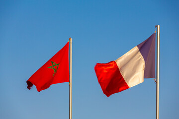 The flag of Morocco and France waving in a blue sky