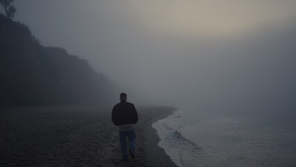 Stylish guy enjoying walk at sea coastline. Sad man looking ocean horizon