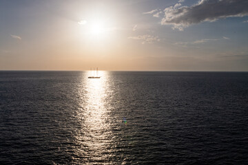 A sailing ship sails through the reflections of the evening sun in the Mediterranean Sea. 