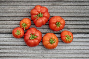 Seven red ripe tomatoes on a wooden floot.