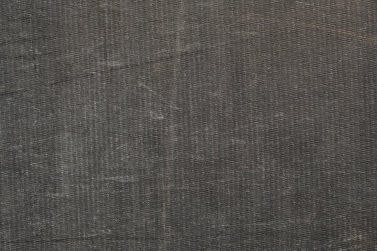 Background of a black awning in close-up. The texture of an old worn tarpaulin. The tent tarpaulin damaged in nature