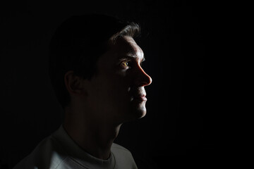 Fototapeta na wymiar profile of thoughtful man looks to the right. portrait in side light, hard light, photo on black
