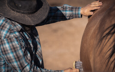 Obraz premium Veteran Cowboy Brushing Horse