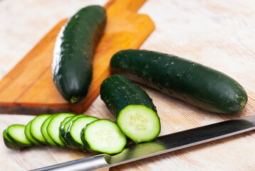 Close up of cut fresh green cucumbers on wooden background, nobody