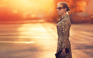 Stylish model woman posing in evening wearing dress with leopard print on city street