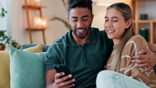 Phone, happy and couple on social media in the house and enjoy scrolling and sharing funny online content together. Smile, interracial and young woman laughing at memes with Indian partner on sofa
