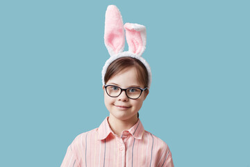 Portrait of cute girl with Down syndrome wearing Easter bunny ears against blue background