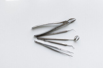 Metal tools of the dentist on a white background. Aesthetics of dentistry. forceps, tweezers, mirror, curettes and scalers