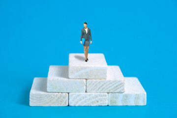 Businessmen standing using binoculars above white stair podium. Miniature tiny people toys photography. isolated on blue background.
