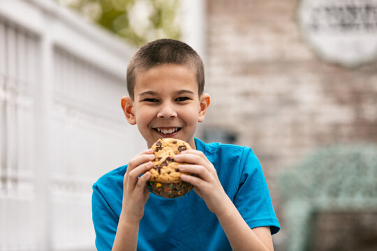 Boy Looks To Camera Eating Giant Ice Cream Cookie Sandwich
