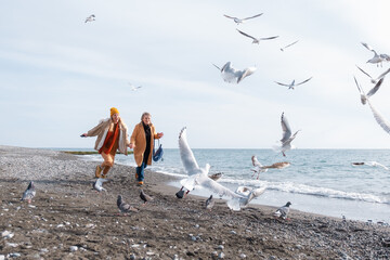 Mom and daughter chasing birds on beach