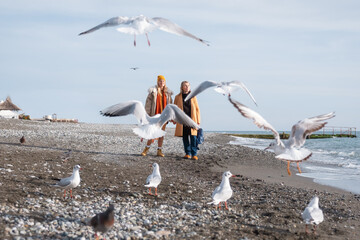 Mother and daughter resting on beach near seagulls