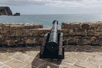 Budva, Montenegro - September 18, 2021:  An old cannon on the fortress of the old town stone castle listed UNESCO World Heritage Sites. Tourism and traveling concept.  Attraction for European tourists