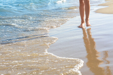 Woman walking on sandy beach near sea, closeup. Space for text