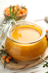Delicious sea buckthorn jam and fresh berries on white wooden table, closeup