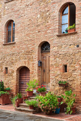 Fototapeta na wymiar Italy, Tuscany, Pienza. Flower pots and potted plants decorate a narrow street in a Tuscany village.