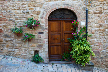 Fototapeta na wymiar Italy, Tuscany, Volterra. Homes along a street surrounded by flower pots in the medieval town of Volterra.