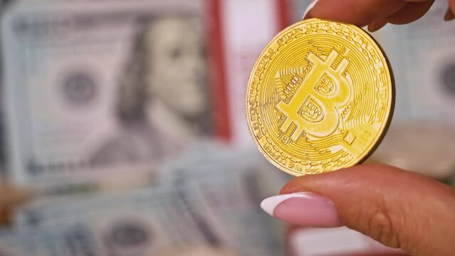 Gold coin of bitcoin on the background of one hundred dollar bills. Cryptocurrency is measured in dollars. Bitcoin BTC coin on 100 dollar bill. Cyberspace of digital coins and cryptocurrencies.