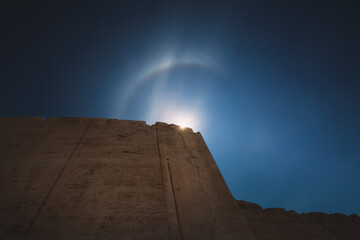 rainbow in the sky. Marble mine. Blue sky. phenomenon. Tall wall. Desert. Sun rays.