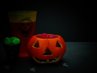 Halloween treat in a ceramic pumpkin and in glasses on a black background.