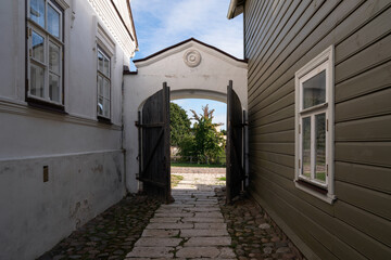 View of the wooden gate to the courtyard of a traditional merchant estate on the main street of Izborsk Pechorskaya Street on a sunny summer day, Izborsk, Pskov region, Russia