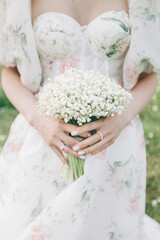 Bride in a white dress holding a bouquet of flowers. Bride holding gentle wedding bouquet.