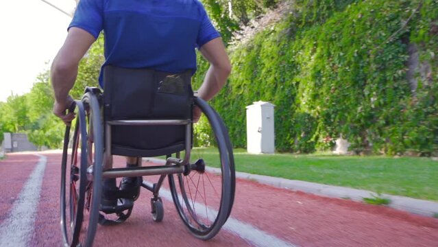 Young disabled person driving a wheelchair in slow motion.
Disabled man in a wheelchair climbs a long ramp along the road.
