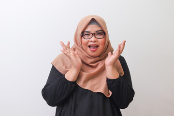 Portrait of cheerful Asian woman with hijab, holding her hands on chin and cheeks. Isolated image...