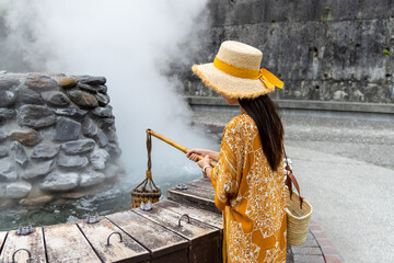 Travel woman put a basket into hot spring for cooking in Jioujhihze of Taipingshan in Taiwan
