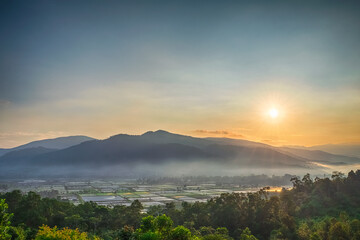 a landscape view of rice or paddy fields and mountain taken from hills at sunrise