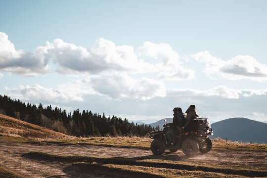People on ATV are driving offroad in mountains during autumn sunny day