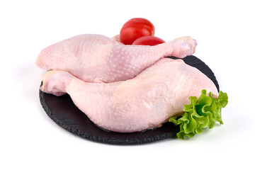 Raw chicken leg quarters on a stone plate, isolated on white background.