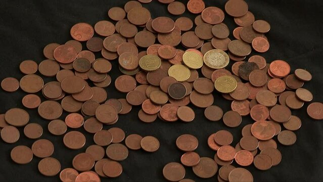 A hand pulling out 1 euro and cent coins that are placed on a dark cloth