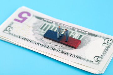 Miniature businessman and magnet on dollar