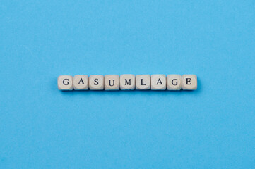 German word Gasumlage means in Englisch gas surcharge, made of wooden cubes placed on blue...