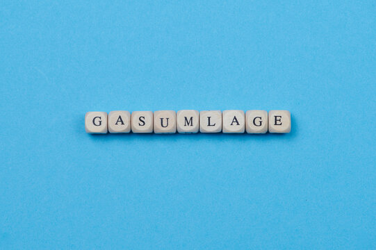 German word Gasumlage means in Englisch gas surcharge, made of wooden cubes placed on blue background