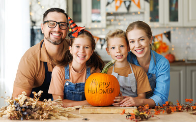 Fototapeta premium Happy family mother, father and children smiling at camera with pumpkin during celebration, preparing home Halloween decorations