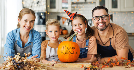 Fototapeta premium Happy family mother, father and children smiling at camera with pumpkin during celebration, preparing home Halloween decorations