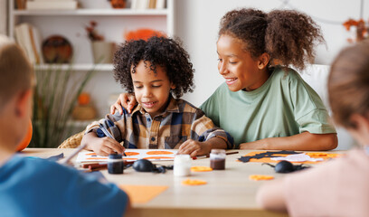 Happy multinational group of children making Halloween home decorations together