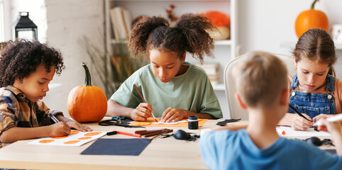 Happy multinational group of children making Halloween home decorations together