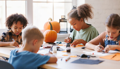 Fototapeta Happy multinational group of children making Halloween home decorations together obraz