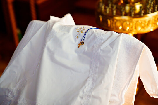 a white baptismal shirt and a cross on a table in the church during baptism.