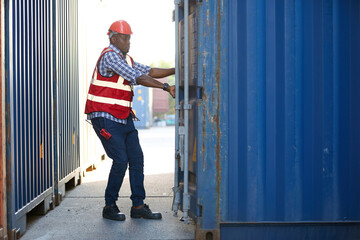 African factory worker or foreman opening the container door in warehouse storage