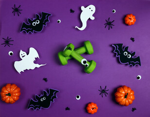 Green dumbbells with Halloween decorations on purple background.